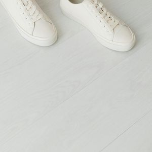 A pair of clean white training shoes on light floor